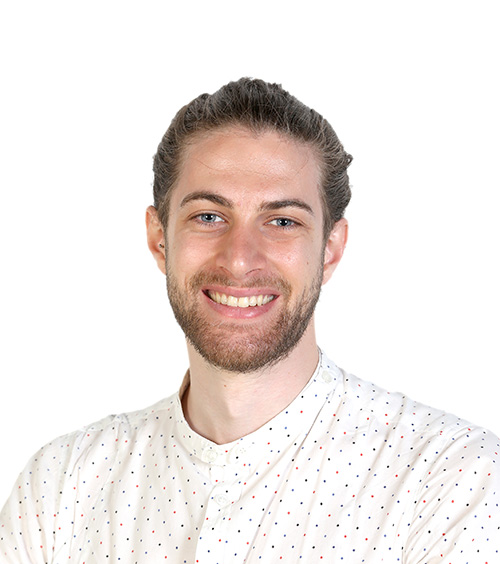 Photograph of a white man, wearing a white collarless shirt, smiling towards the camera.