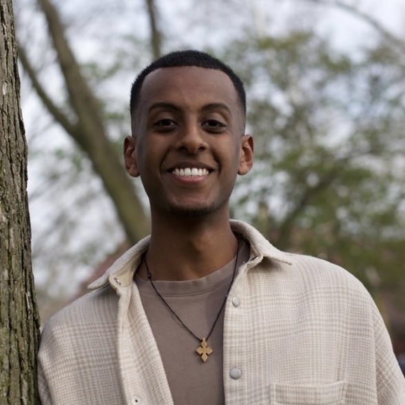 Headshot of a smiling man next to a tree.